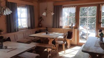 A cozy room with wooden furniture, large windows, and a view of a snowy landscape.