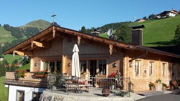 A traditional wooden building with a balcony, a statue, and a stone wall in front.