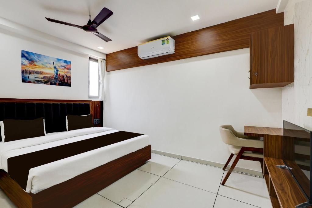 A hotel room with a bed, a desk, and a ceiling fan.