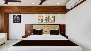 Une chambre d’hôtel moderne dotée d’un grand lit, de ventilateurs de plafond, d’un appareil de climatisation et d’œuvres d’art accrochées aux murs.