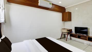 Habitació d'hotel amb un llit, una televisió, escriptori i aire condicionat.