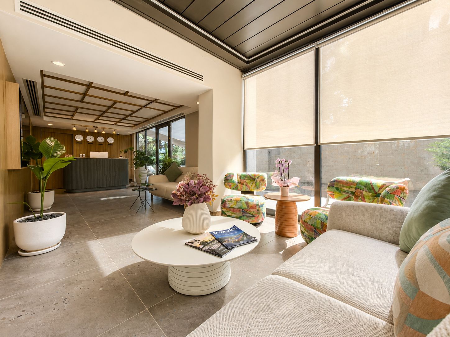 Un hall d’hôtel moderne avec un comptoir d’accueil, un espace salon et de grandes fenêtres.