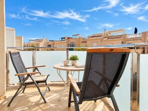 Eine Terrasse mit zwei Stühlen und einem Tisch mit Blick auf eine Wohngegend.