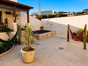A rooftop patio with a hammock, potted plants, and a small seating area.