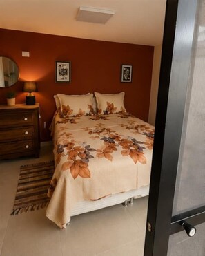 A bedroom with a bed, a nightstand, a lamp, and a wall-mounted picture. - Studio 442 (Águas de São Pedro)