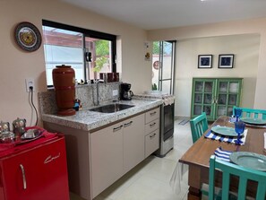 A compact kitchen with a sink, stove, and a dining area with a table and chairs.