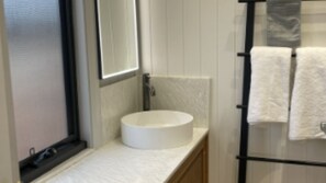 Ein Badezimmer mit einem weißen Waschbecken, einem Spiegel und einem Handtuchhalter mit Handtüchern.