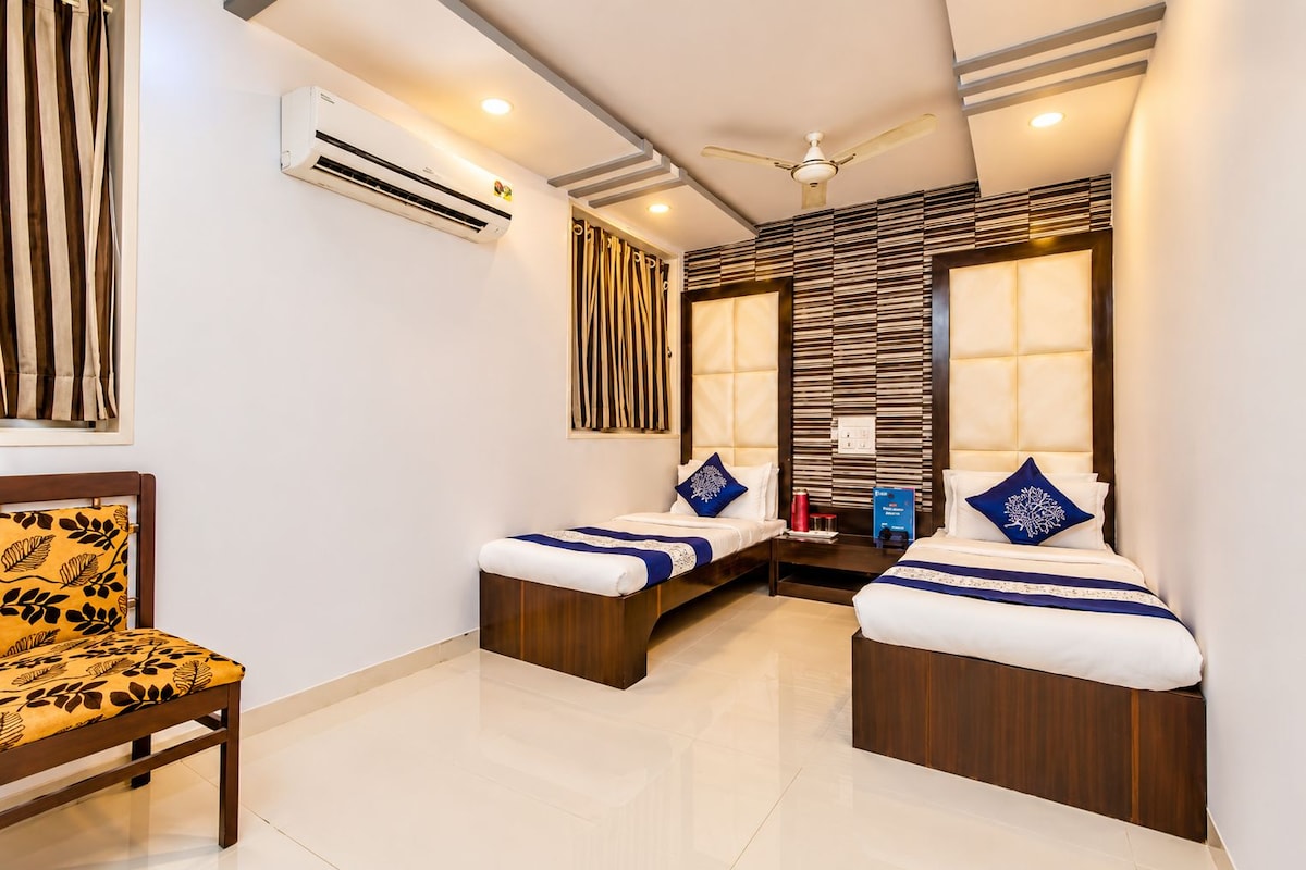 A hotel room with two beds, a ceiling fan, an air conditioning unit, and a wooden chair.
