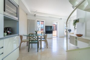 Ett modernt kök med matplats, TV och en trappa som leder till ett annat våningsplan.