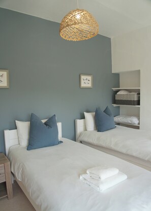 A hotel room with two beds, a hanging light fixture, and a wall-mounted shelf with baskets. - Large modern farmhouse, surrounded by 40 acres of private countryside (Unknown)