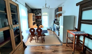 Una cuina compacta amb zona de menjador, armaris de fusta, nevera i un penjol.