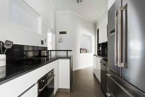 Eine moderne Küche mit einem Edelstahlkühlschrank, einer schwarzen Arbeitsplatte und weißen Schränken.