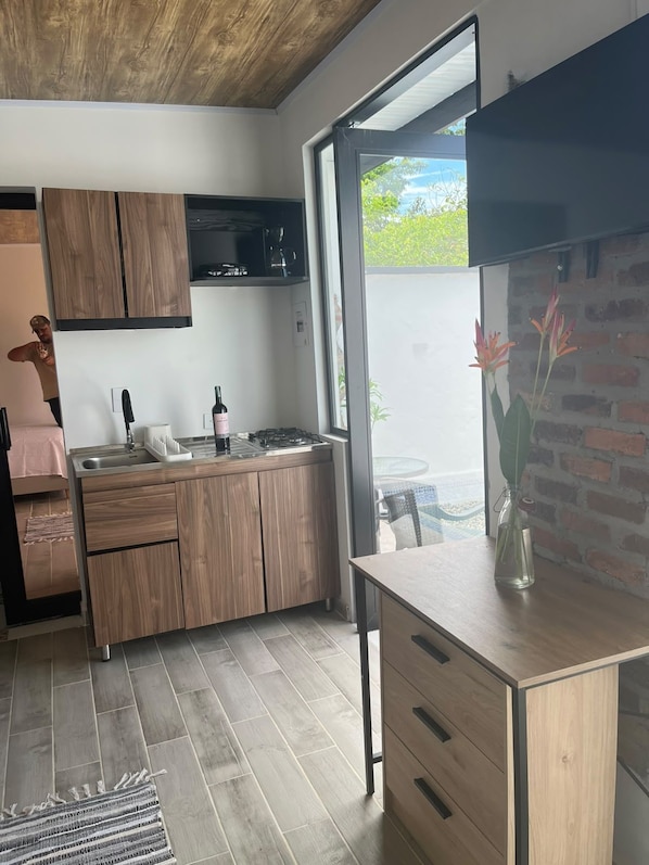 A modern kitchen with wooden cabinets, a gas stove, and a large window offering a view of the outdoors. - Vrbo Property (Meta)