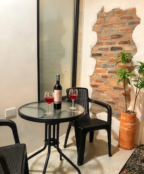 Uma mesa redonda pequena com duas cadeiras, uma garrafa de vinho e dois copos de vinho tinto.