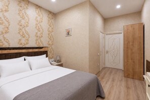 A bedroom with a bed, bedside table, lamp, and a wardrobe. - Midcity Hotel (Baku)