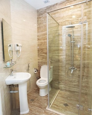 A bathroom with a glass-enclosed shower, a pedestal sink, and a toilet. - Midcity Hotel (Baku)