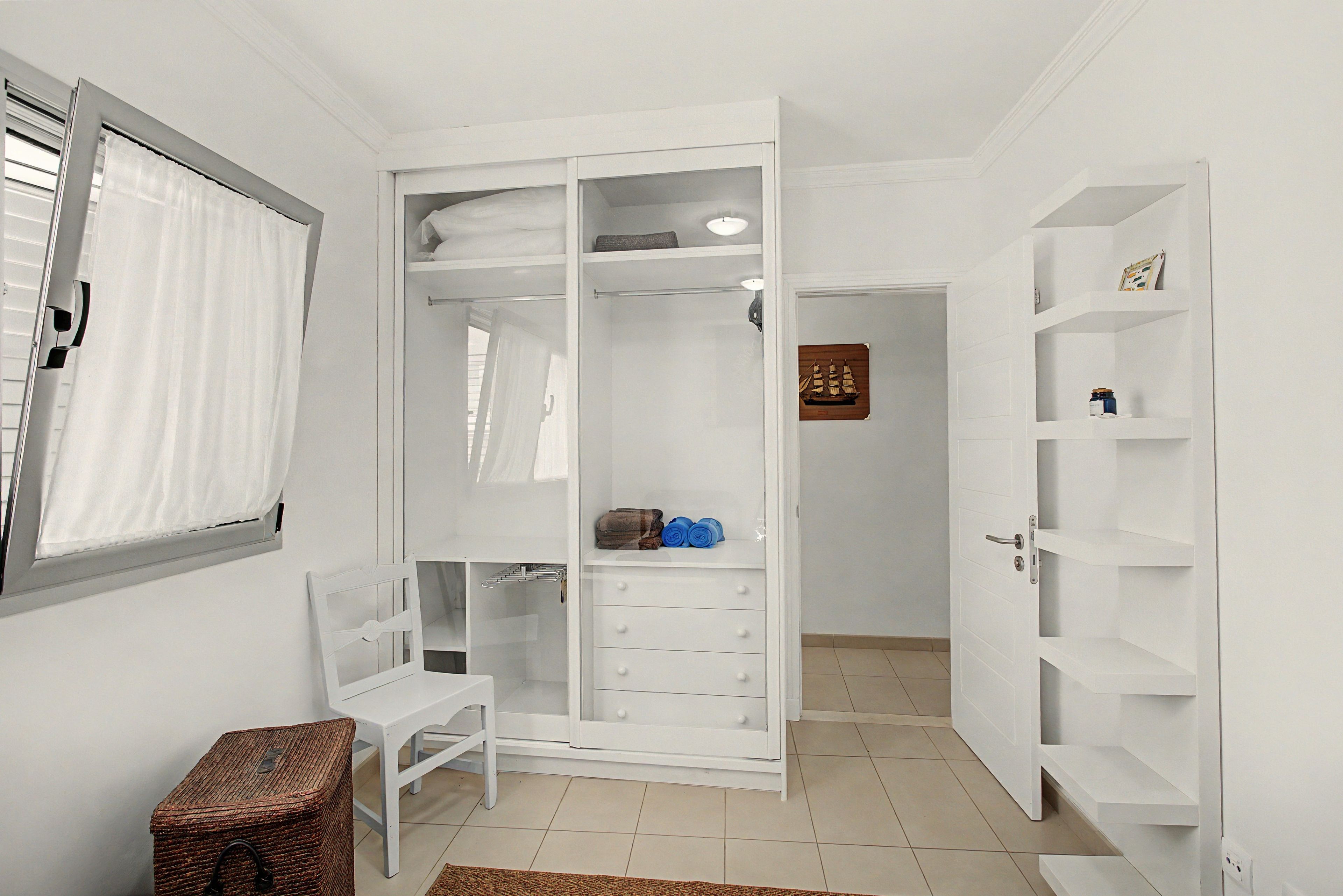 Un vestidor amplio con puertas abiertas, estantes y una pequeña mesa.