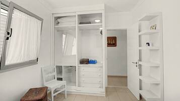 Un vestidor amplio con puertas abiertas, estantes y una pequeña mesa.