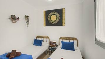 Una habitación con dos camas individuales, un adorno en la pared y una mesita con un libro.