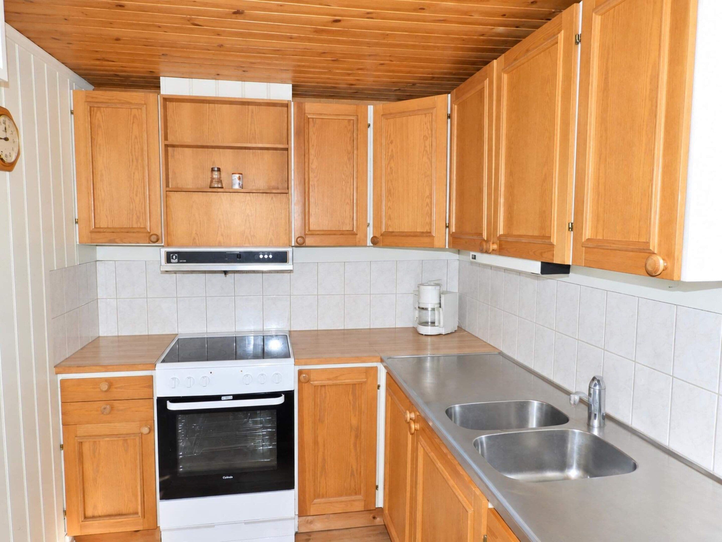 A kitchen with wooden cabinets, a built-in oven, a coffee maker, and stainless steel sinks.