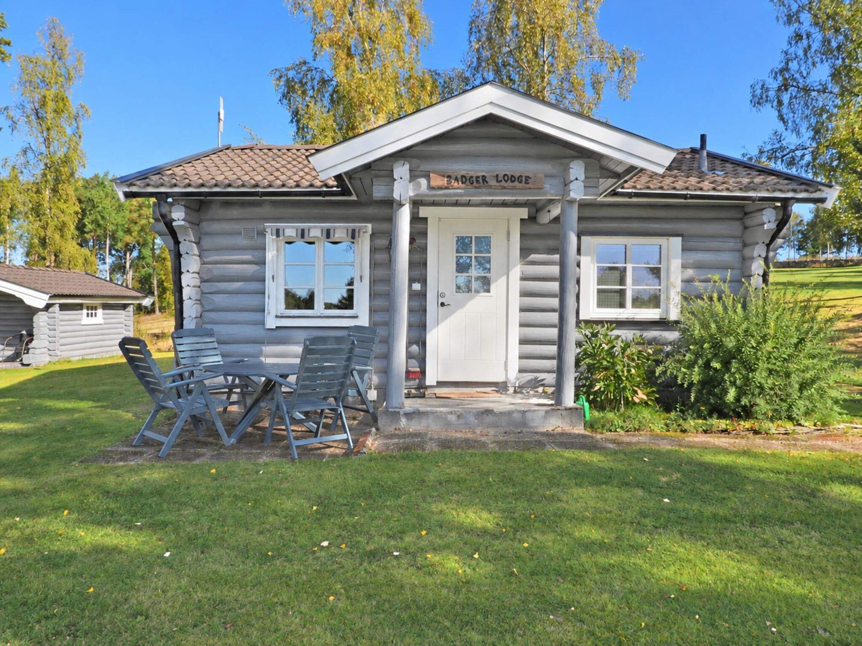 A log cabin with a front porch, two windows, and a sign that reads 'Badger Lodge.'