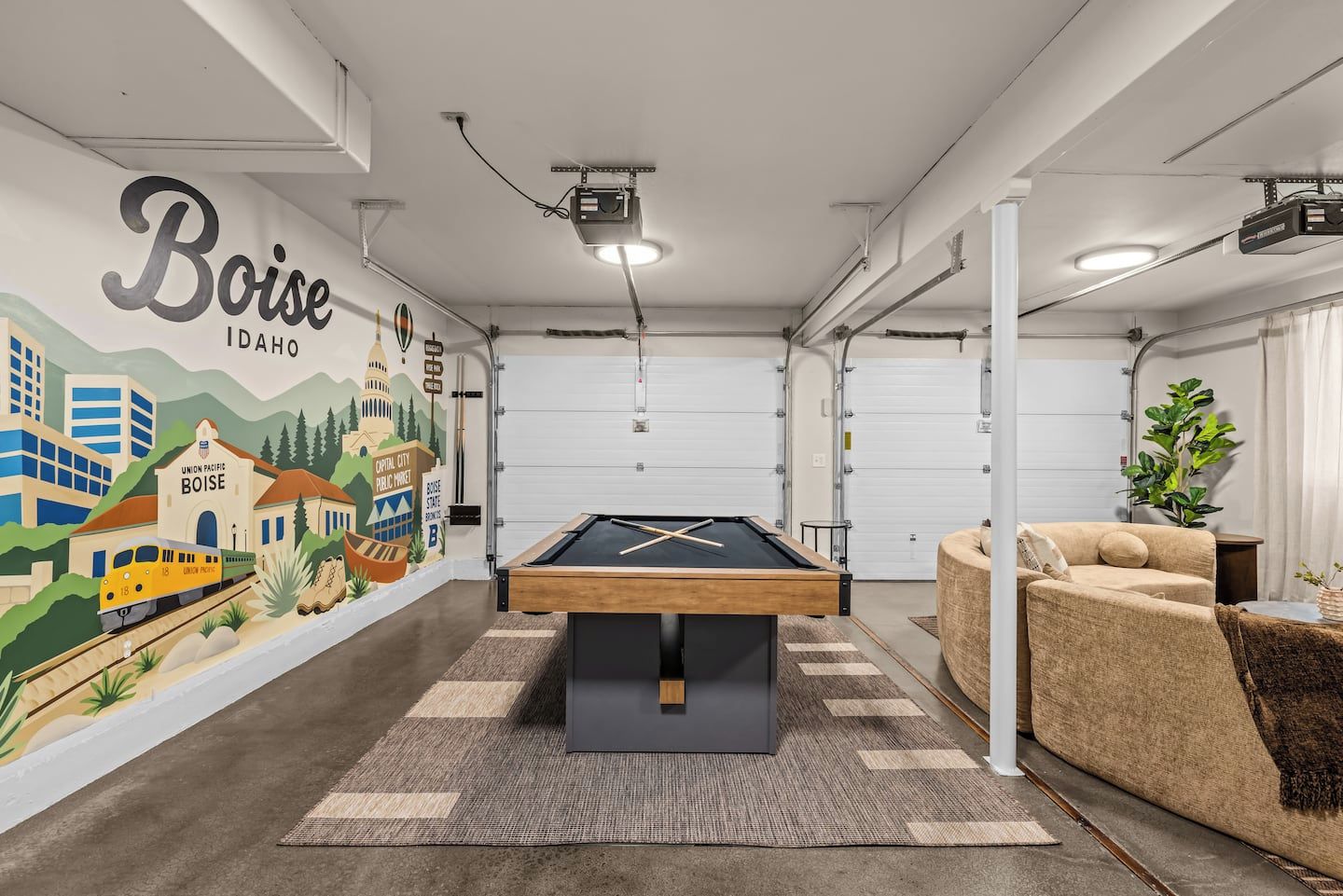 Una mesa de billar en una habitación con un mural de Boise, Idaho, un sofá y una planta.