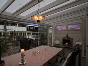 A covered outdoor dining area with a table, chairs, a grill, and a fire feature. - 6 Person Holiday Home in Tyresjo (Tyreso)