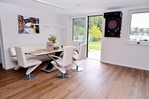 Una zona de menjador moderna amb taula de vidre, caires blancs i un joc de daus.