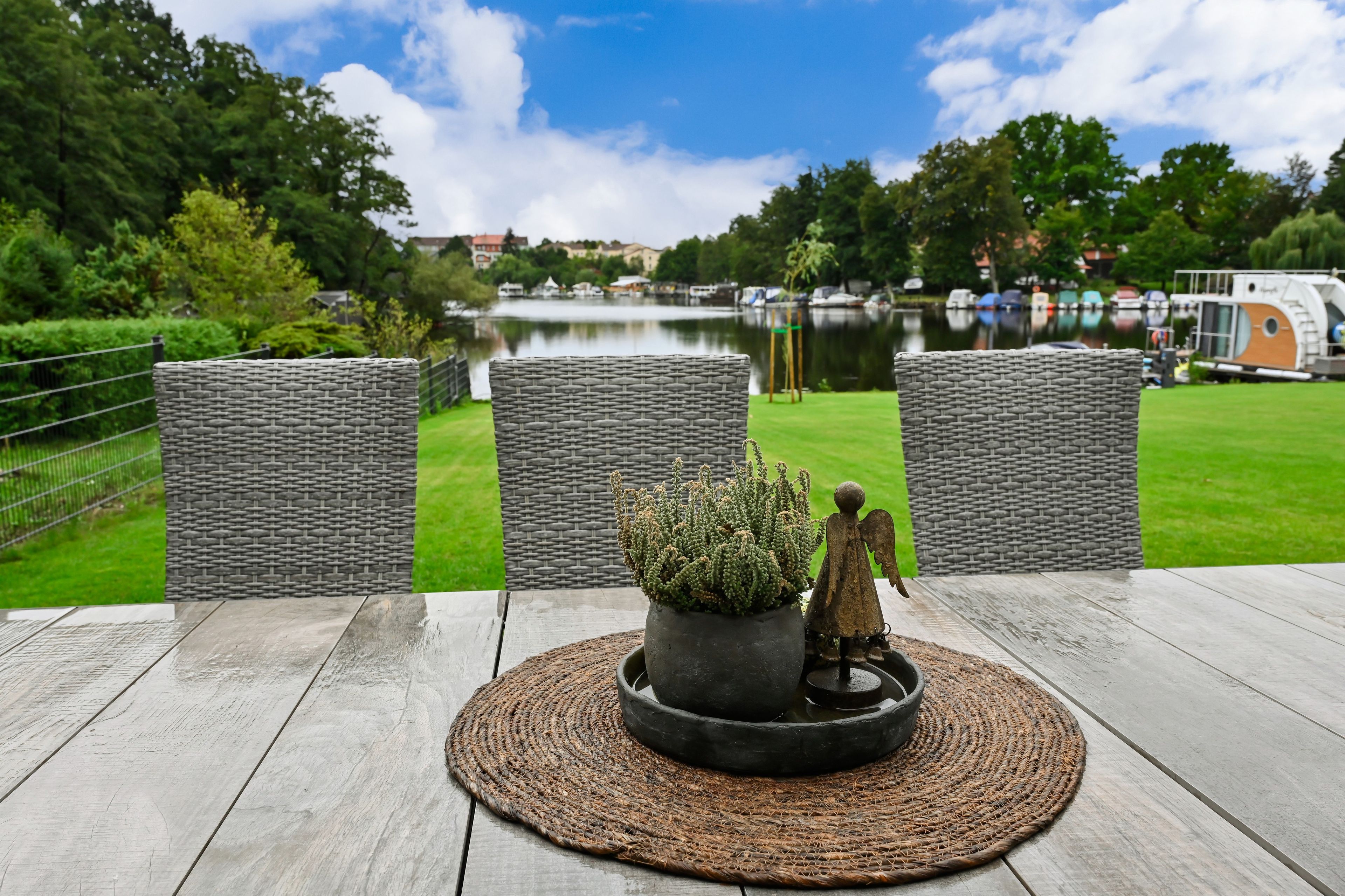Eine Terrasse mit Korbstühlen, einem Blumentopf und einer kleinen Engelsfigur.