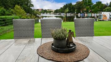Eine Terrasse mit Korbstühlen, einem Blumentopf und einer kleinen Engelsfigur.