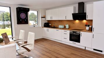 A modern kitchen with white cabinetry, a wooden countertop, and a dartboard on the wall.