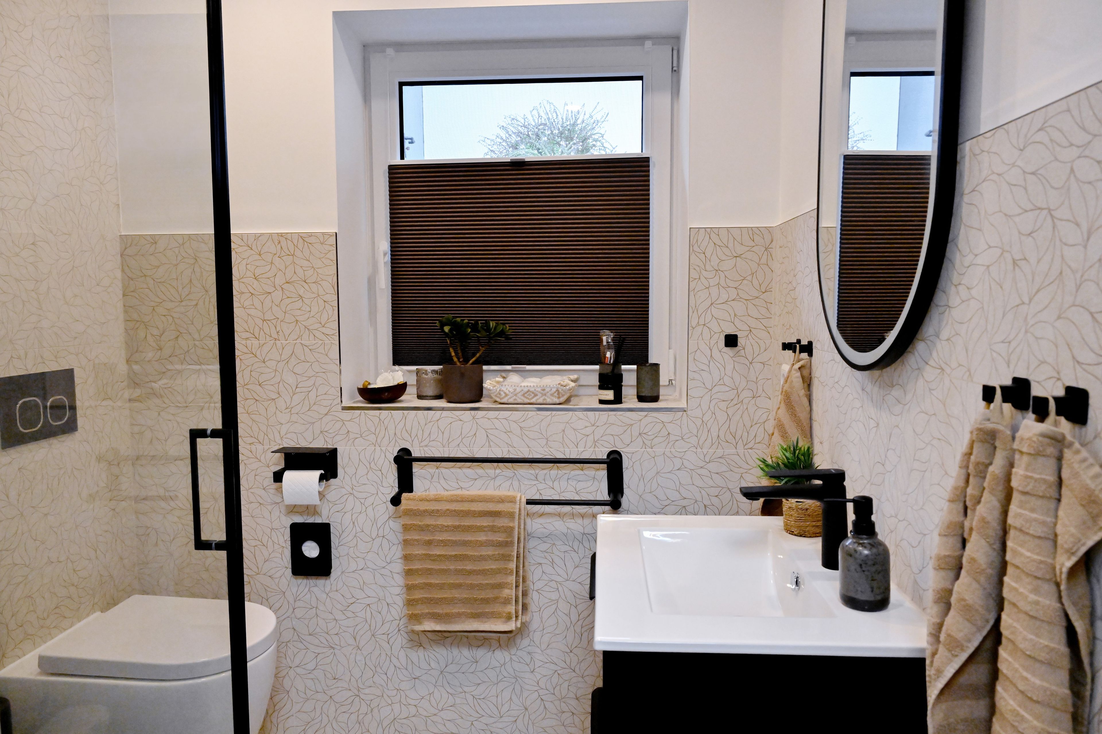 A bathroom with a toilet, sink, towel rack, and window with blinds.