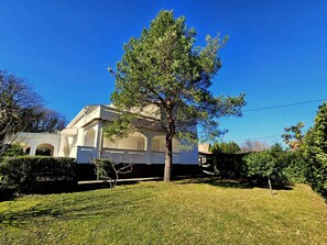 Un edificio con un árbol grande al frente, rodeado por un césped cuidado.