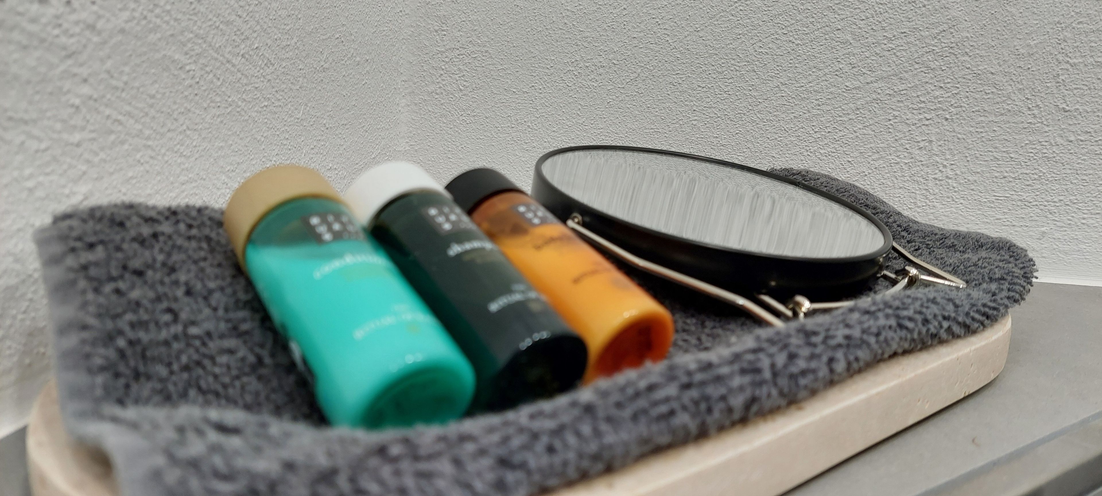 A tray with three bottles and a magnifying glass on a textured surface.