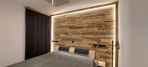 Un dormitorio con una cama, un panel decorativo de madera y una mesita de noche.