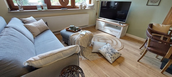 Una sala de estar con sofá, mesa de centro, televisor y piso de madera.