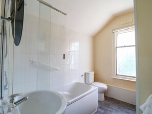 A bathroom with a bathtub, toilet, and a window. - Dover Retreat (Ipswich)