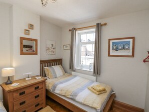Ein Schlafzimmer mit Bett, Schminktisch und einem Fenster mit Vorhängen.