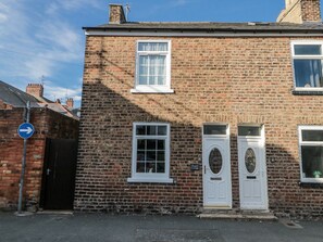 A two-story brick building with a white door and windows, a blue directional sign, and a small sign reading 'Chapel Cottage'. - Chapel Cottage (Filey)