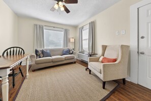 A living room with a sofa, armchair, dining table, and a ceiling fan. - Midtown Mobile Gem Near Downtown (Mobile)
