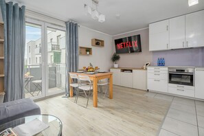 Eine moderne Wohnung mit Essbereich, Küche und einem großen Fenster mit Vorhängen.