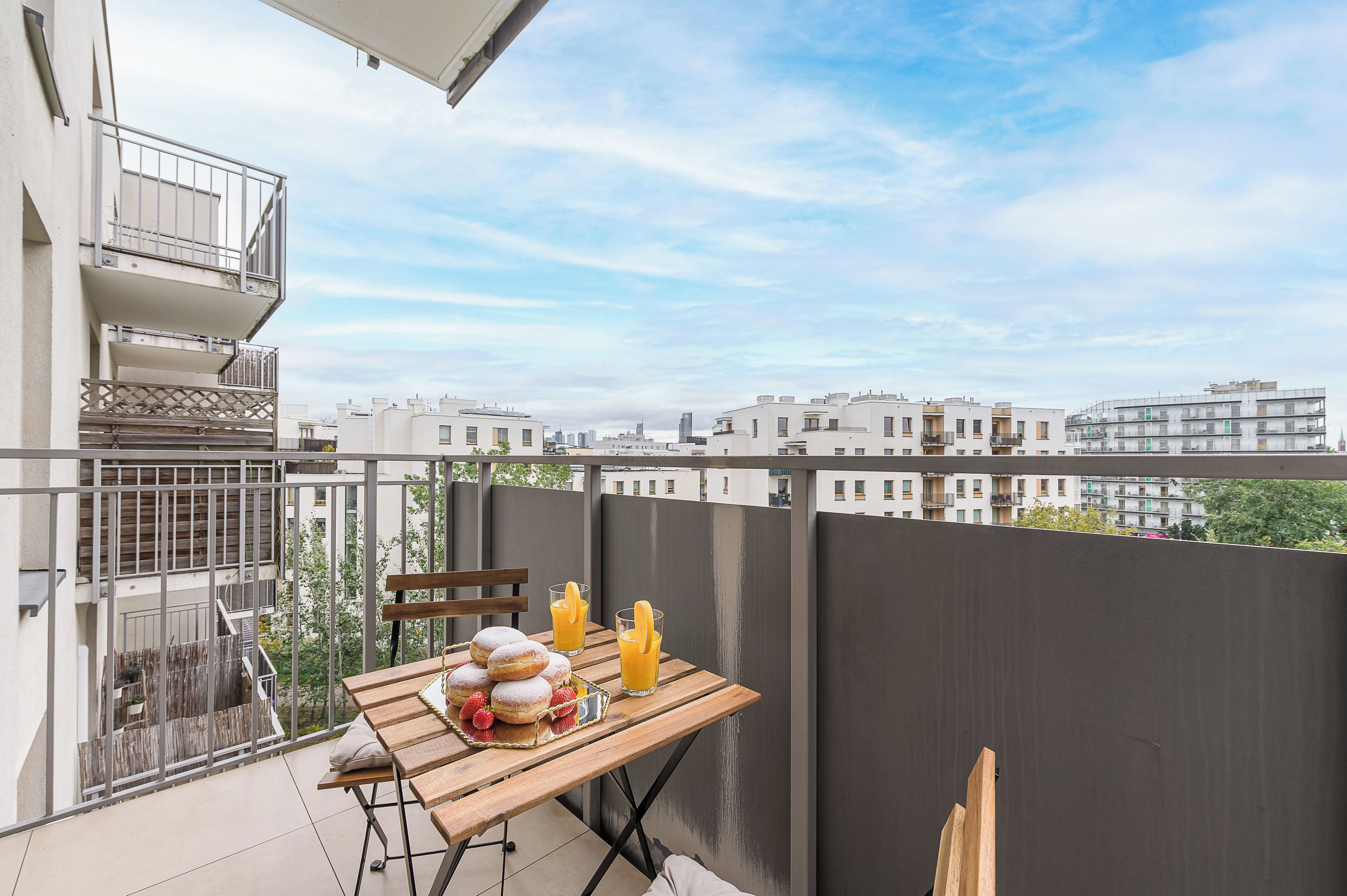 Ein Balkon mit Frühstückstisch, der auf einen Wohnbereich blickt.