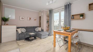 Una sala moderna con un sofá gris, una mesa de centro y una zona de comedor con una mesa de madera y sillas.