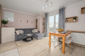 Ein modernes Wohnzimmer mit einem grauen Sofa, einem Couchtisch und einem Essbereich mit einem Holztisch und Stühlen.