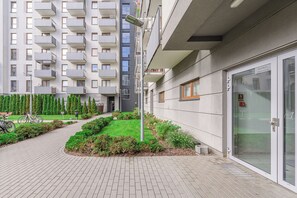 Um edifício moderno com entrada de vidro, um caminho pavimentado e uma área de jardim bem cuidada.