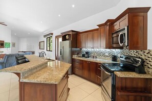 Eine moderne Küche mit Granit Arbeitsplatten, Edelstahlgeräten und Holzschränken.