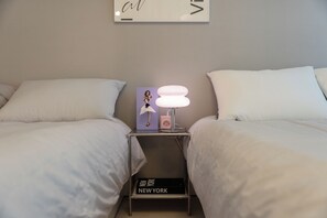 A hotel room with two beds, a nightstand with a lamp, a picture frame, and a book titled 'NEW YORK'. - Seoul Pause (Mapo-gu)