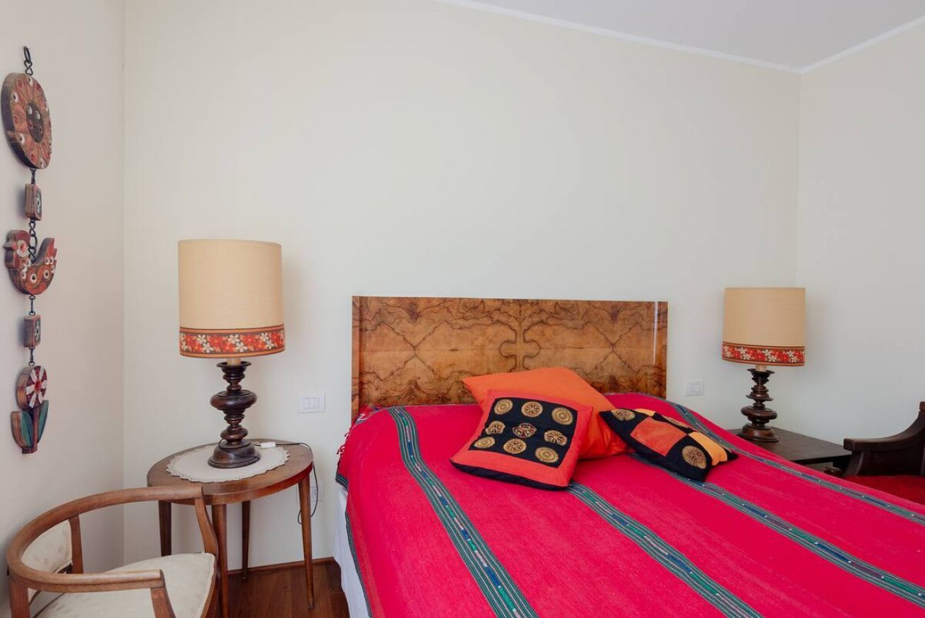 Una stanza con un letto, due lampade da comodino, un tavolino rotondo e una sedia.