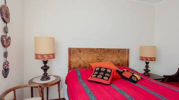Una stanza con un letto, due lampade da comodino, un tavolino rotondo e una sedia.