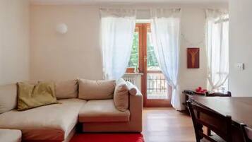 Ein Wohnzimmer mit beiger Couch, einem roten Teppich, einem Holztisch und einem Balkon mit Aussicht.